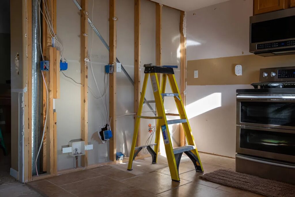 Drywall repair in progress with exposed studs and ladder, surface prep by an interior painter in Westminster, MD