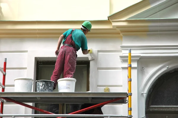 Exterior painter applying white paint to a home’s exterior walls highlighting professional trim painting in Potomac, MD.